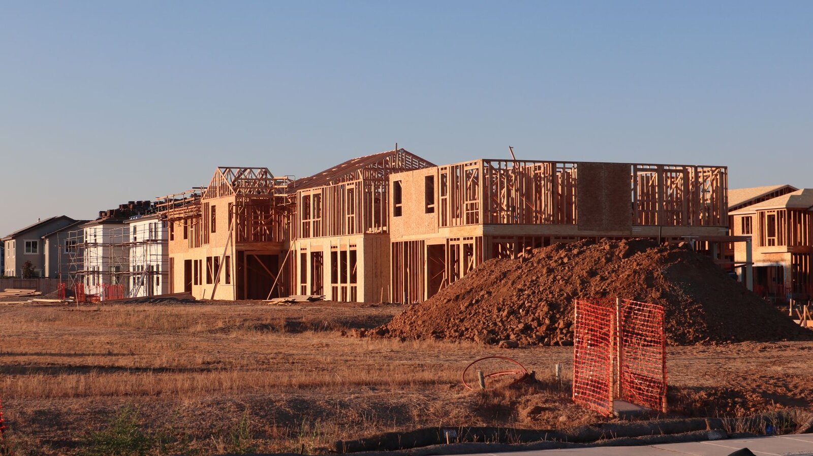 Wood-framed New England homes under construction at golden hour